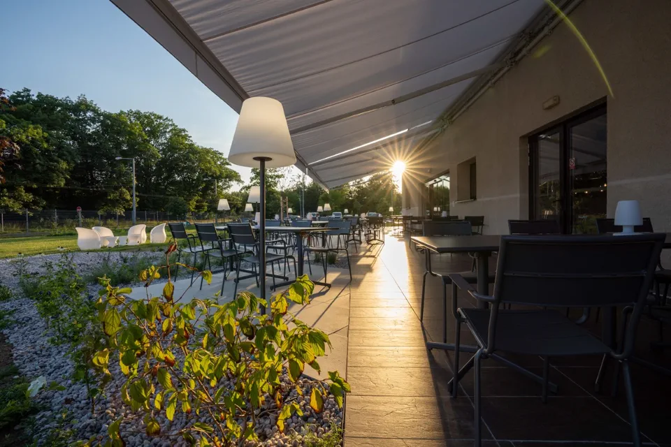 Venkovní terasa Hotelu Ibis Plzeň s posezením obklopená zelení